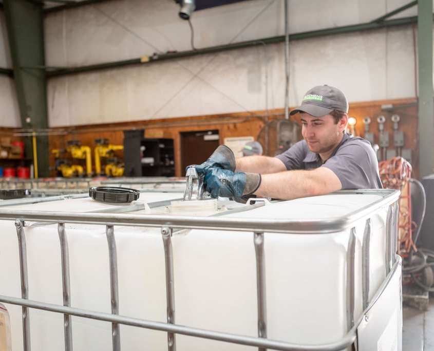 Hutchens Rentz-Eden employee standing next to lubricant storage tank.