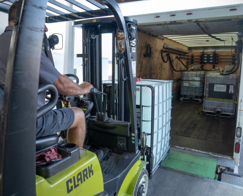 DEF Storage Totes being loaded onto a box truck by an HRE forklift operator.